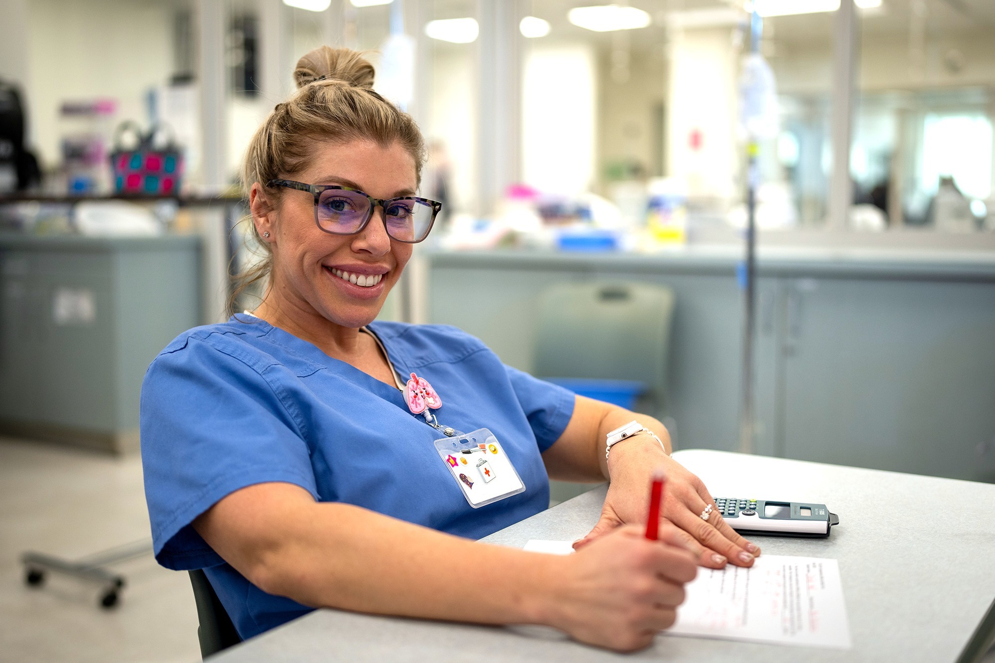 A community health worker in scrubs, smiling and looking at the viewer