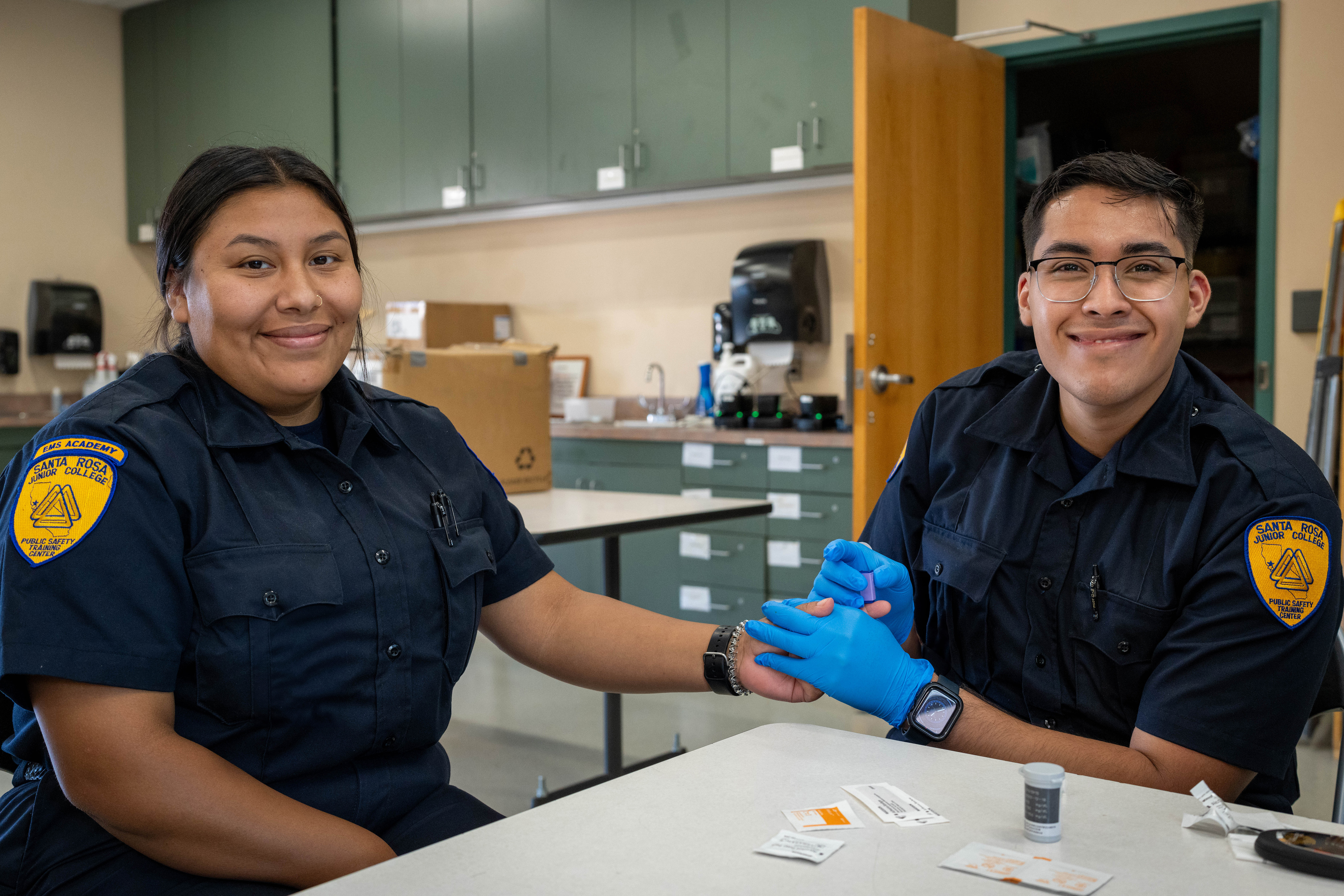 Two SRJC students smiling at the viewer while practicing a procedure